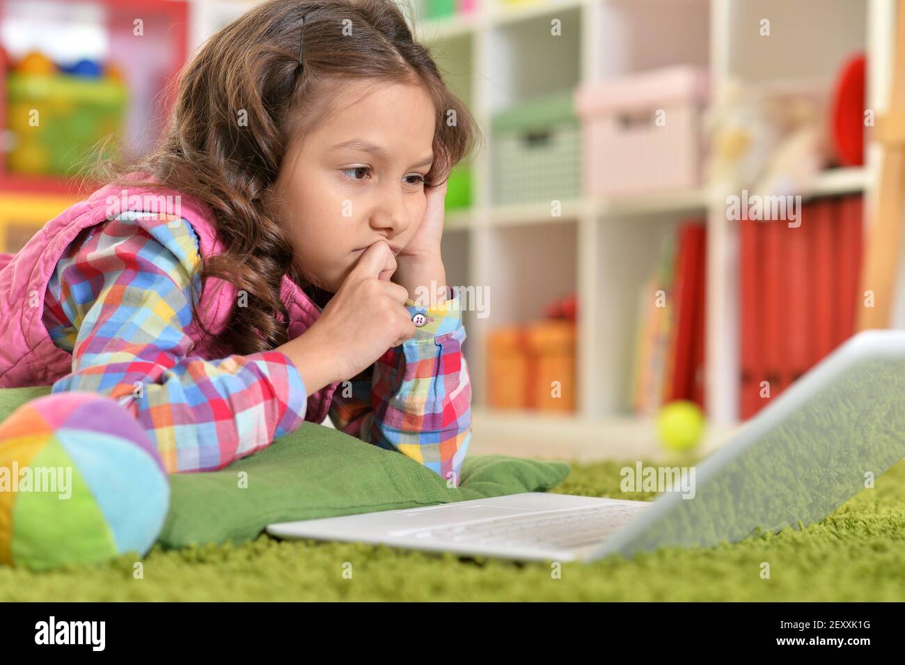 Cute girl using laptop while lying on green floor Stock Photo - Alamy