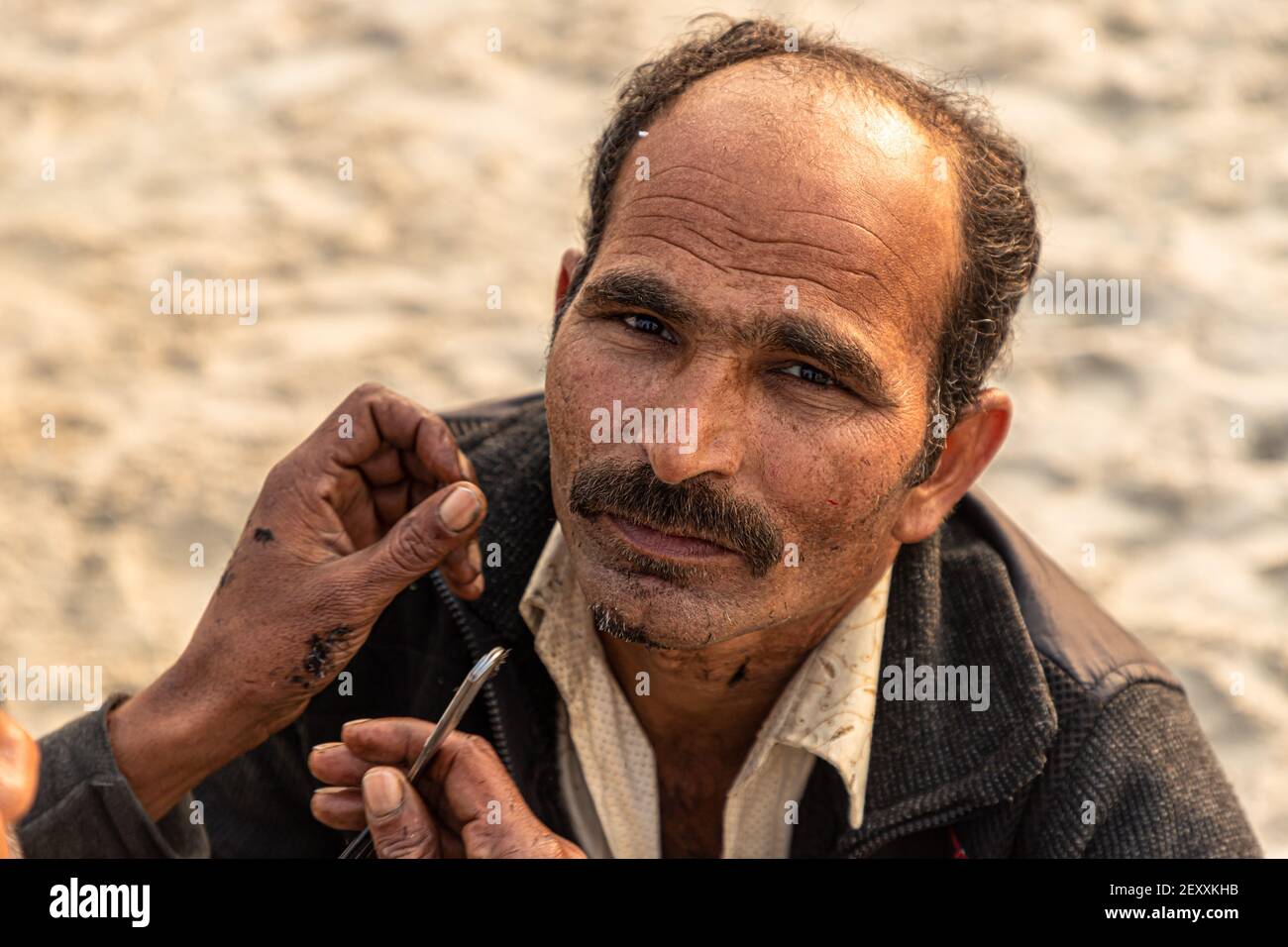 a barber cutting the hair of pilgrim during the kumbh mela in haridawar.kumbh is the largest congregation on the earth. Stock Photo