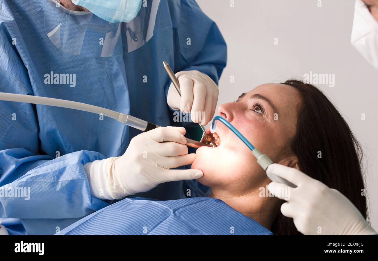 dentist working with personal protective equipment, female patient, in