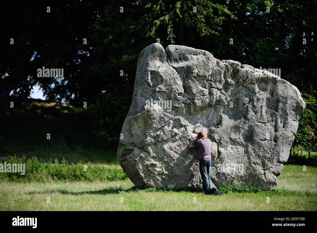 A man leans against a megalith pictured at Avebury's outer circle on
