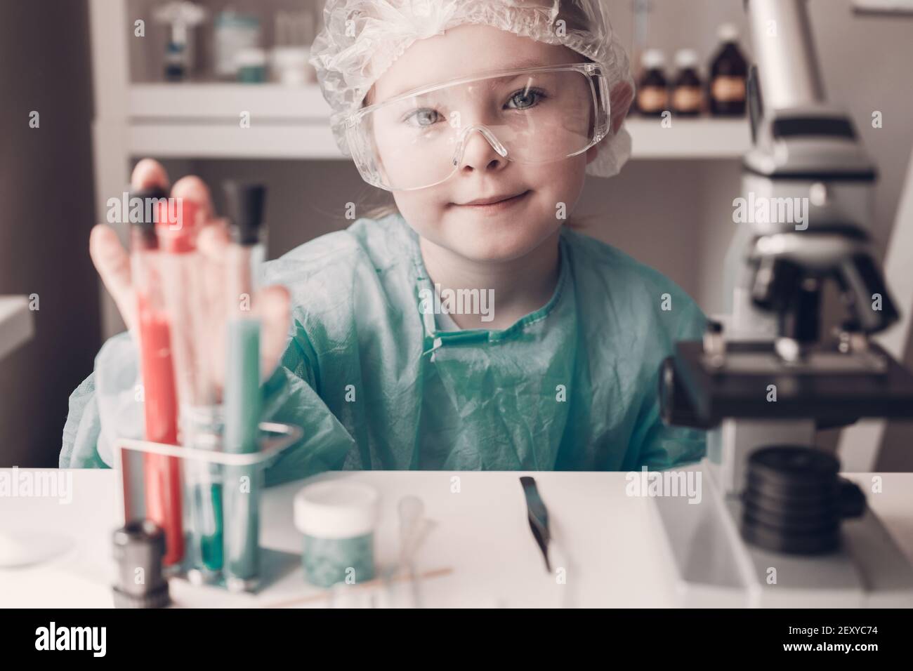 Little girl in lab coat learning chemistry in school laboratory. Young