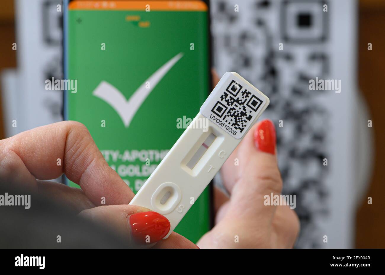 Dresden, Germany. 05th Mar, 2021. A woman holds a Covid-19 rapid test cassette with the negative result in her hands in a pharmacy, in the background the app of the Saxon startup 'pass4all' can be seen on a smartphone. The results are stored in the associated app for the first time. The patent-pending system 'pass4all' will be used throughout Germany and across all industries for digital contact tracing of companies since September 1, 2020, in order to support health authorities quickly and efficiently in the event of an illness. Credit: Robert Michael/dpa/Alamy Live News Stock Photo