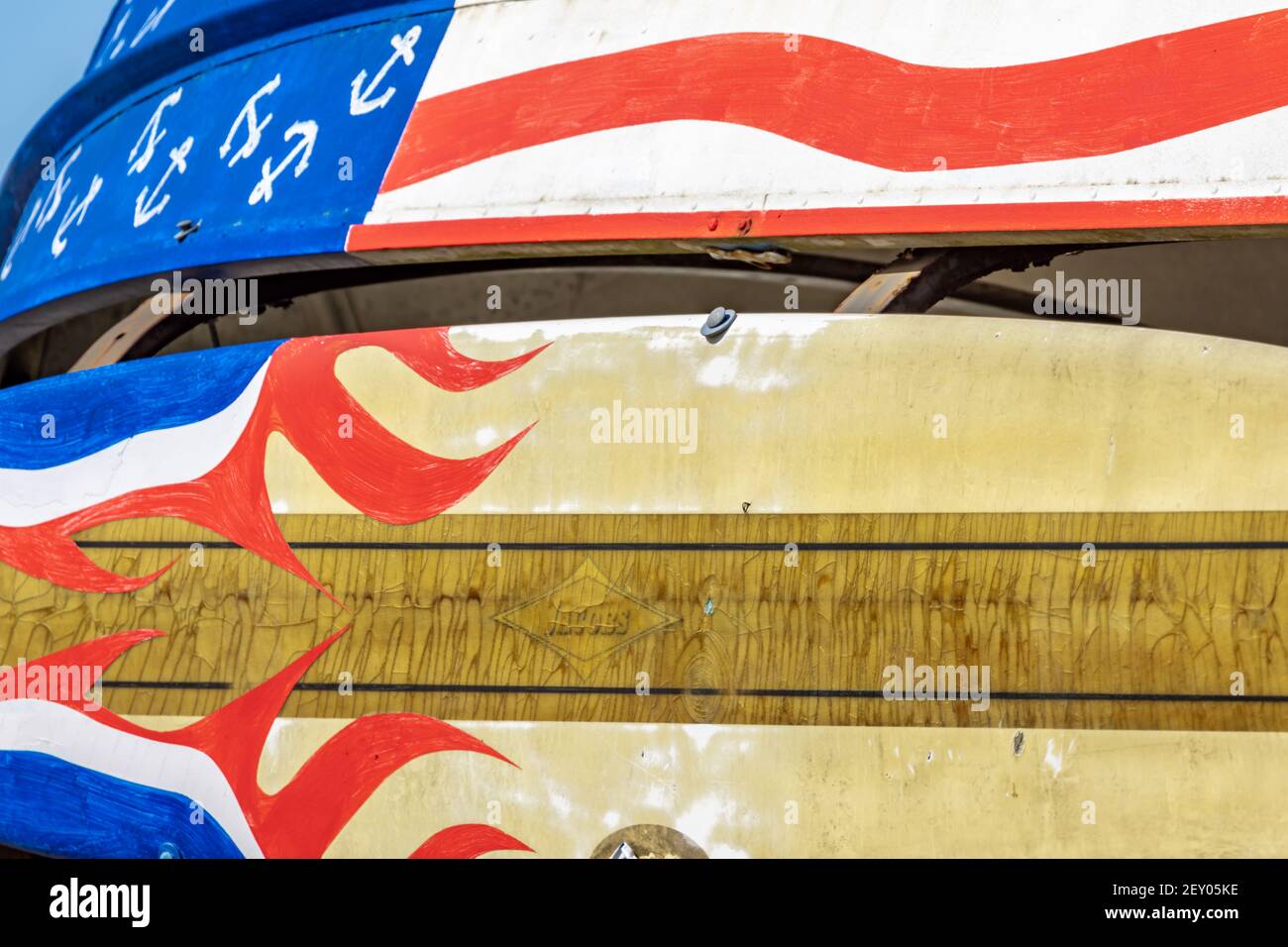 Detail image of a surf board and a small boat painted red, white and blue Stock Photo