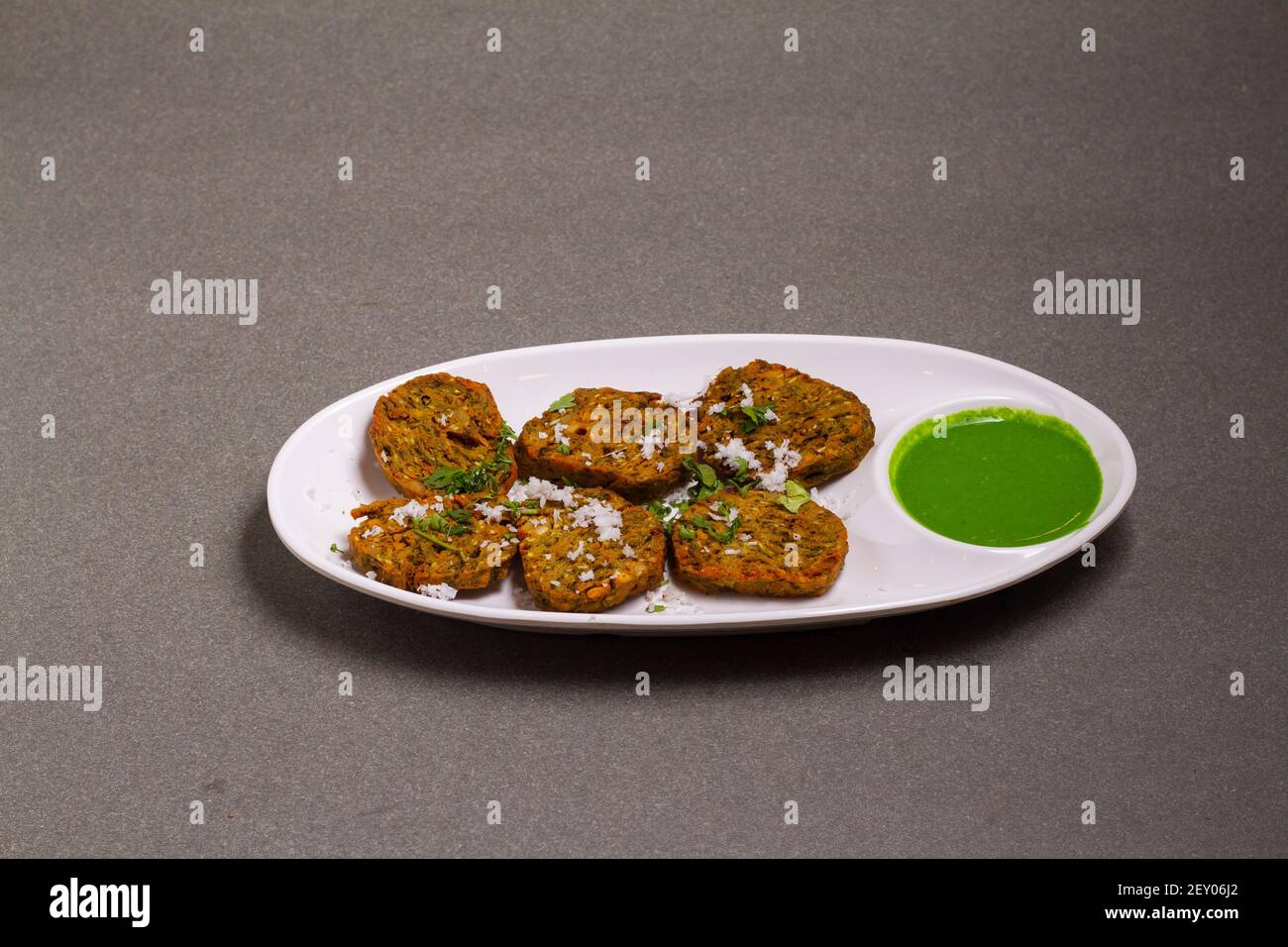 Cilantro cake or Kothimbir Vadi is a popular Maharashtrian cuisine made with cilantro leaves. served with tomato ketchup. selective focus Stock Photo