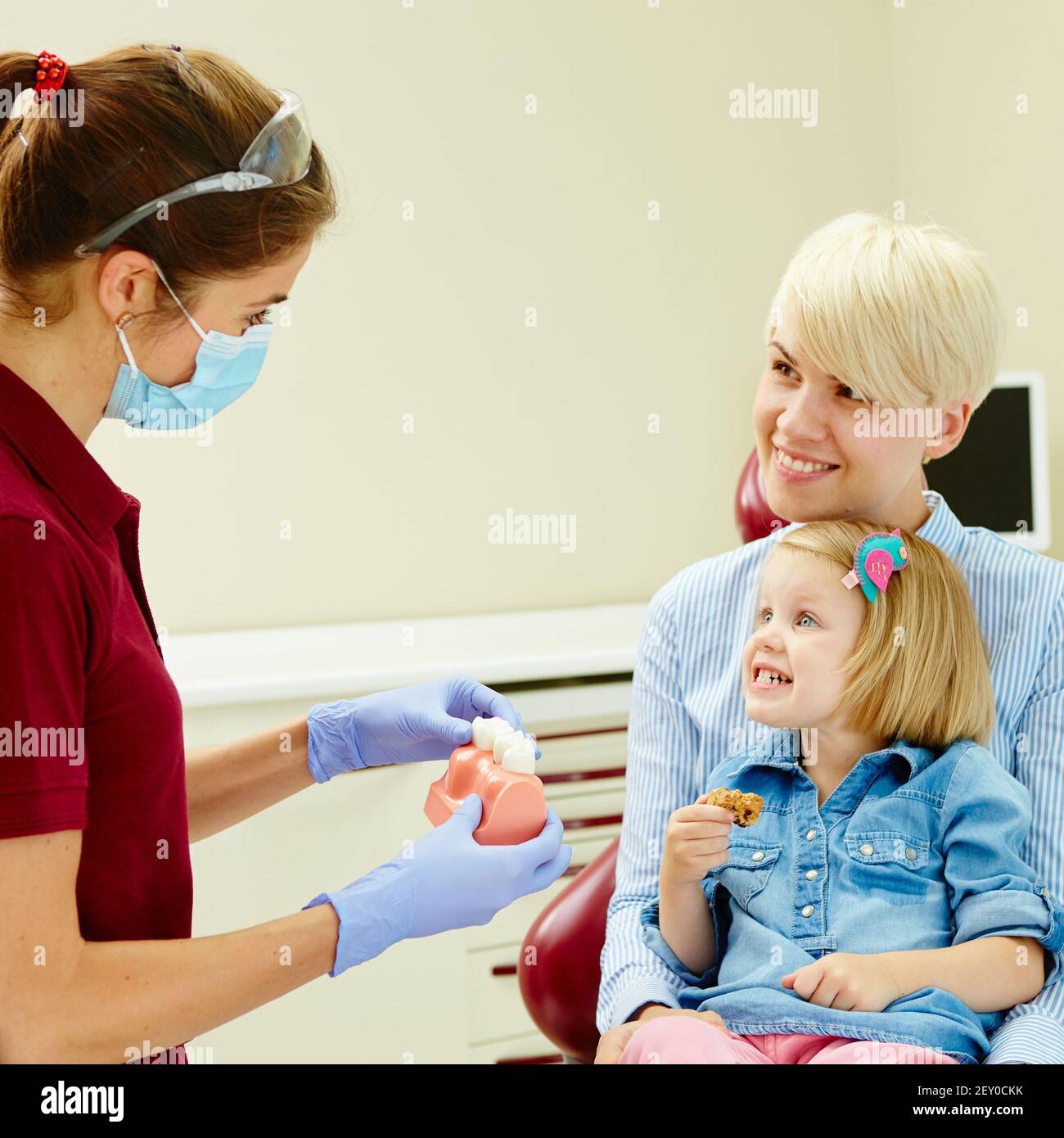 Pediatric dentist explaining to young patient and her mother the model Stock Photo