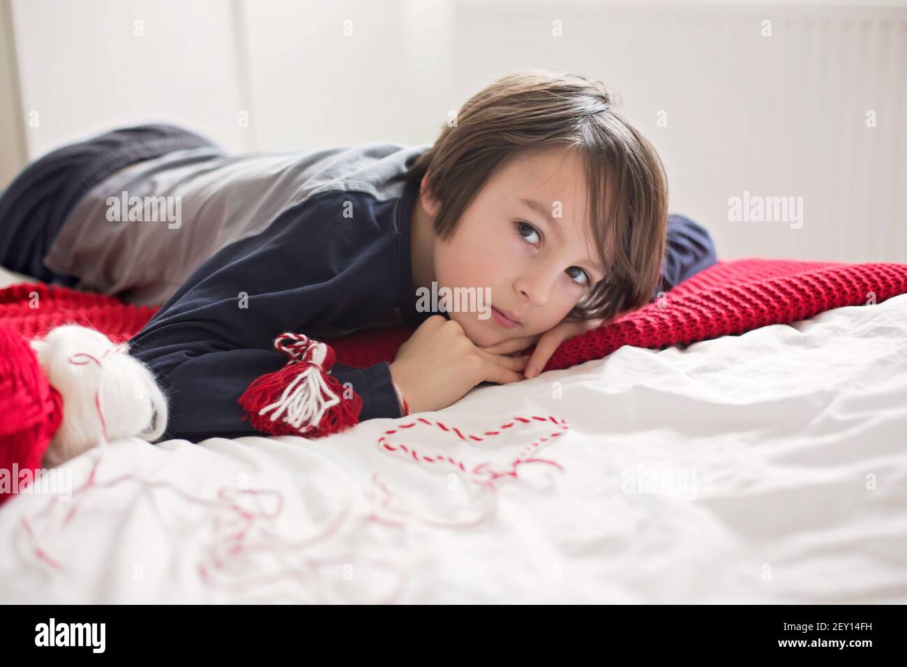 Cute child, blond boy, playing with white and red bracelet, called Martenitsa Stock Photo