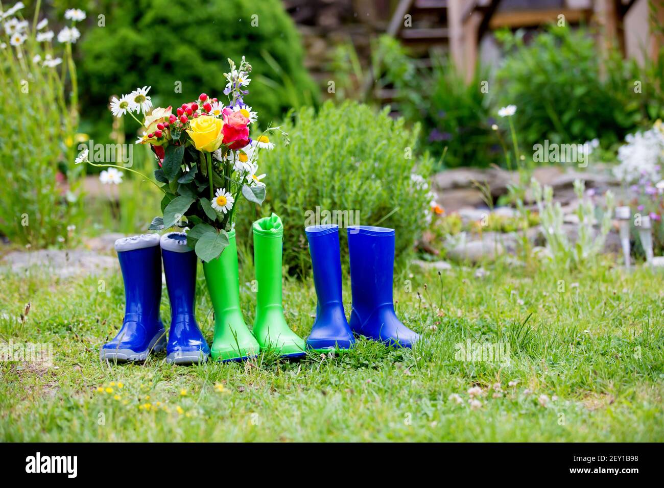 Rubber boots with beautiful flowers in garden Stock Photo
