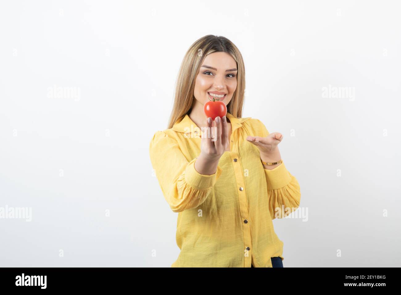Smiling woman holding red tomato on white background Stock Photo - Alamy