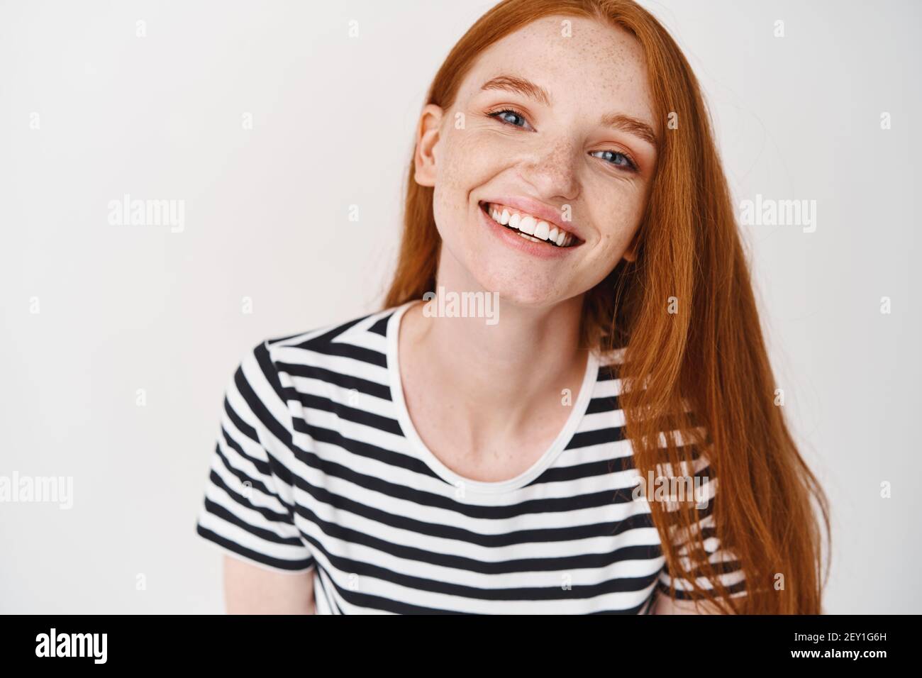 Headshot Portrait of happy ginger girl with freckles smiling looking at