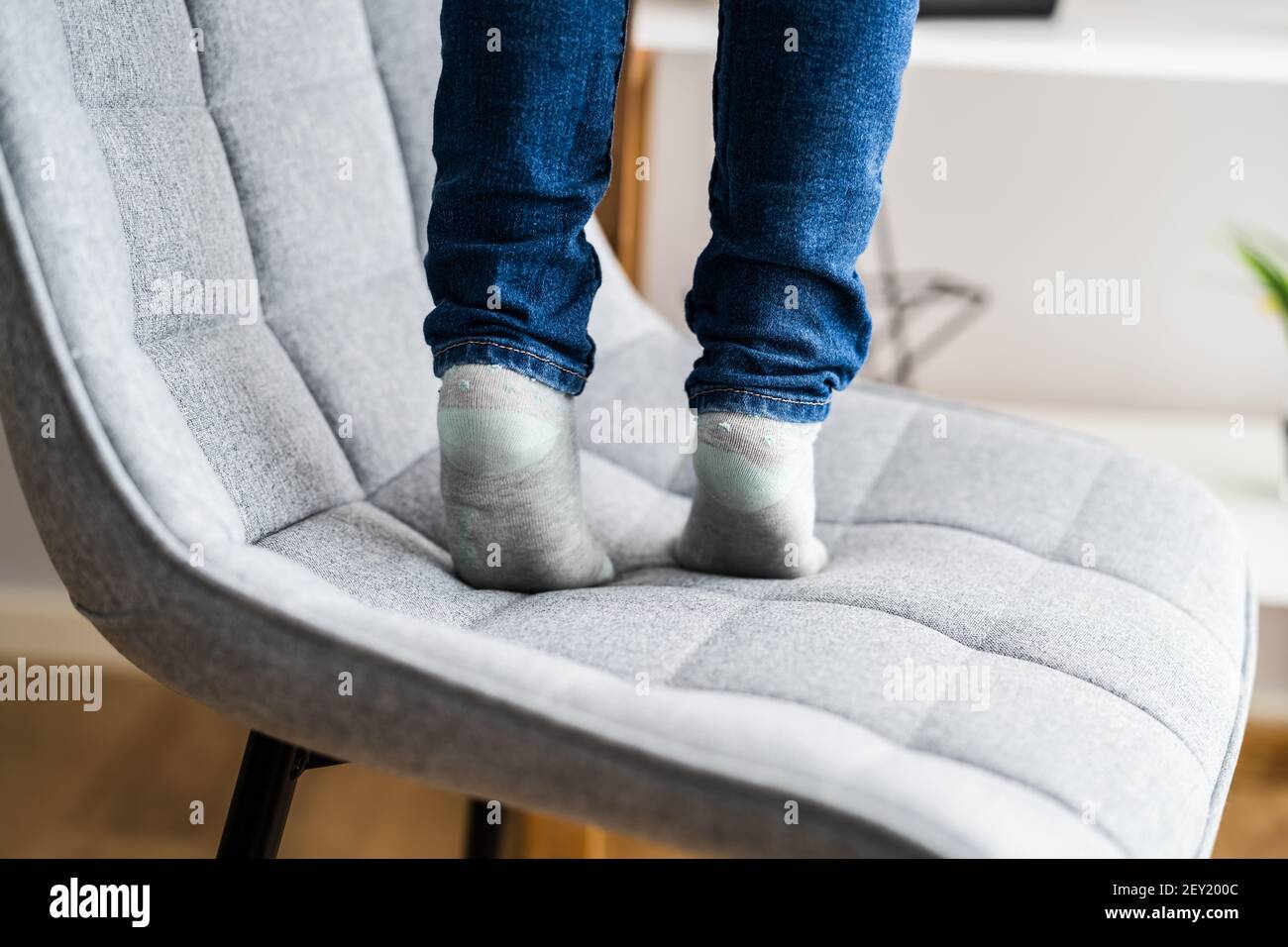 Child Girl Climbing Furniture. Accident Safety In Room Stock Photo