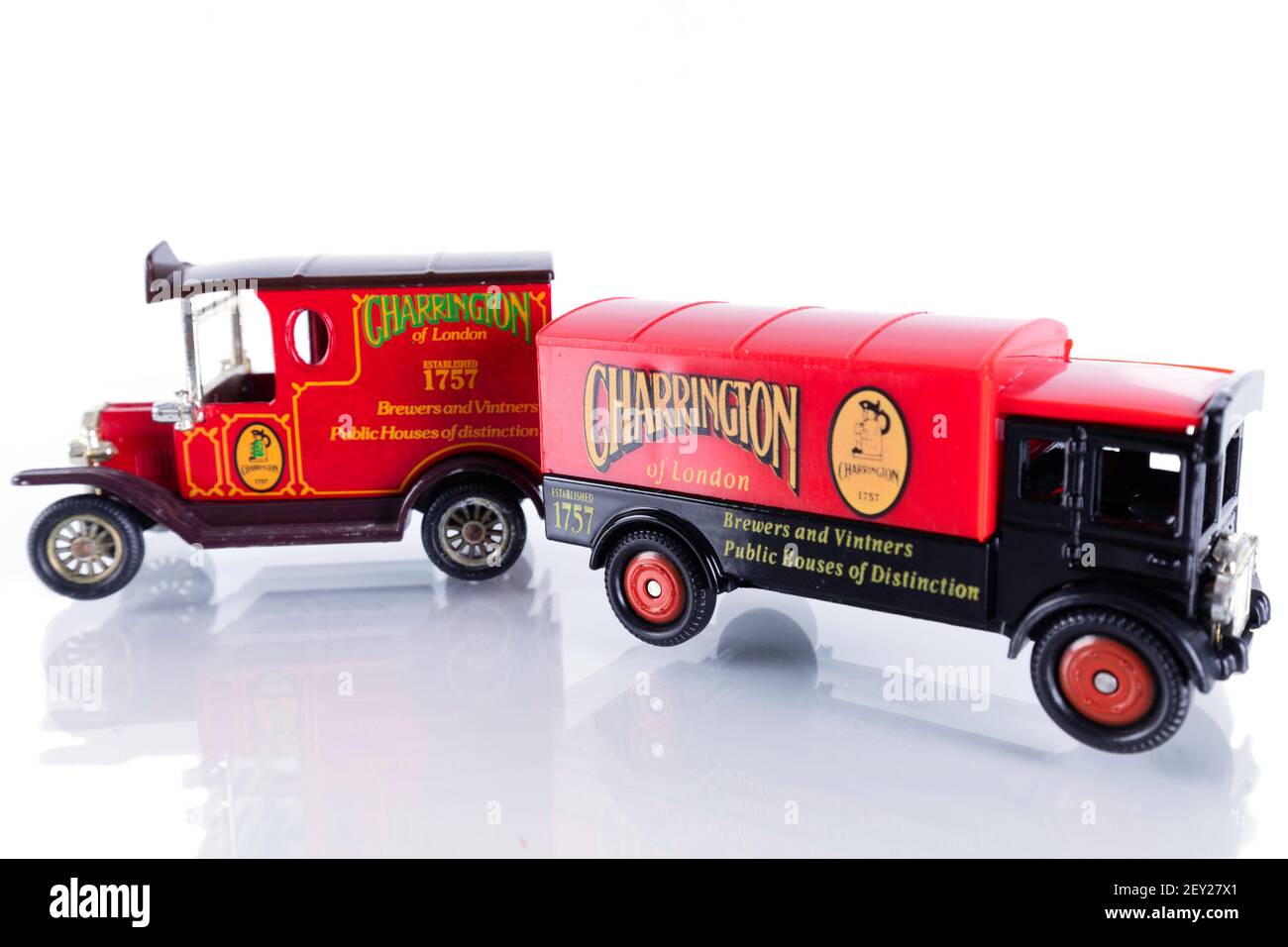 Worn diecast models of vintage 'Charrington' brewer's lorries. Isolated on a white background, with reflection. Stock Photo
