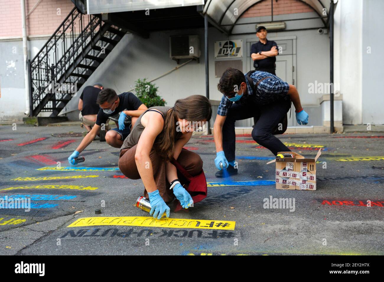 Young girl and boys activists holding spray cans painting offensive letterings against Vladimir Putin on asphalt Stock Photo