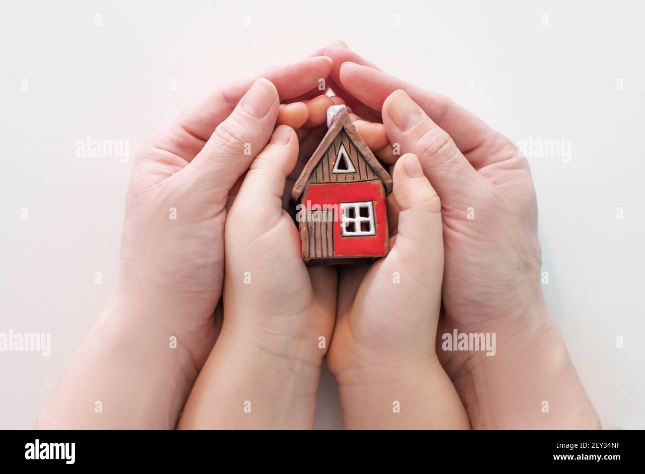 real estate and family home concept - closeup picture of child and female hands holding red paper house with family. High quality photo Stock Photo