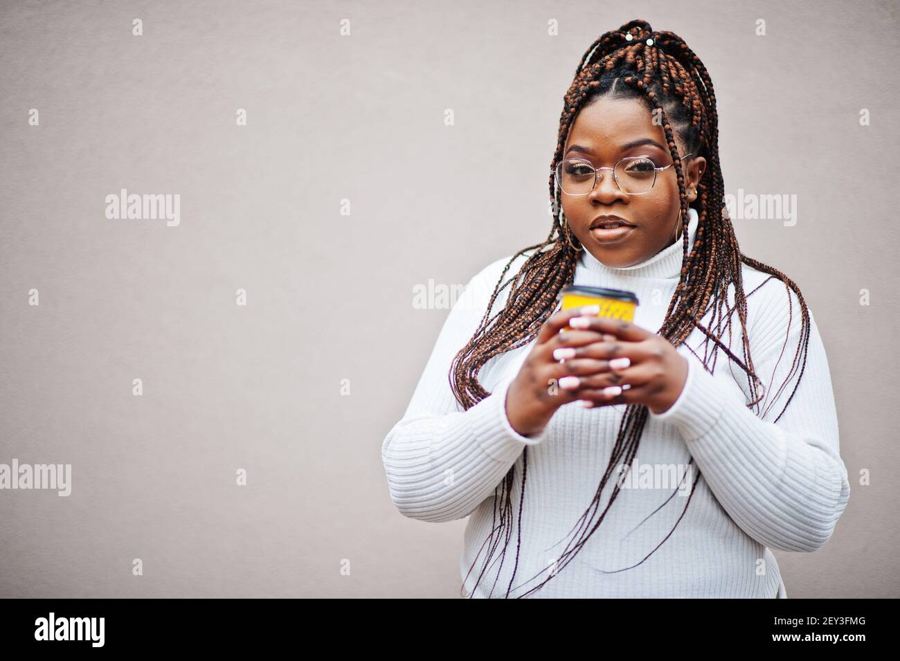 Glamorous african american woman in white turtleneck sweater pose at street  with cup of coffee at hand Stock Photo - Alamy
