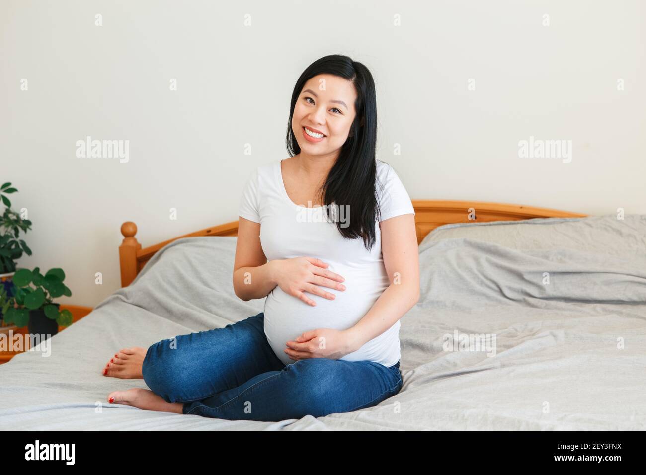 Pregnant Asian Woman Sits On Office Chair Exposing Her Changing