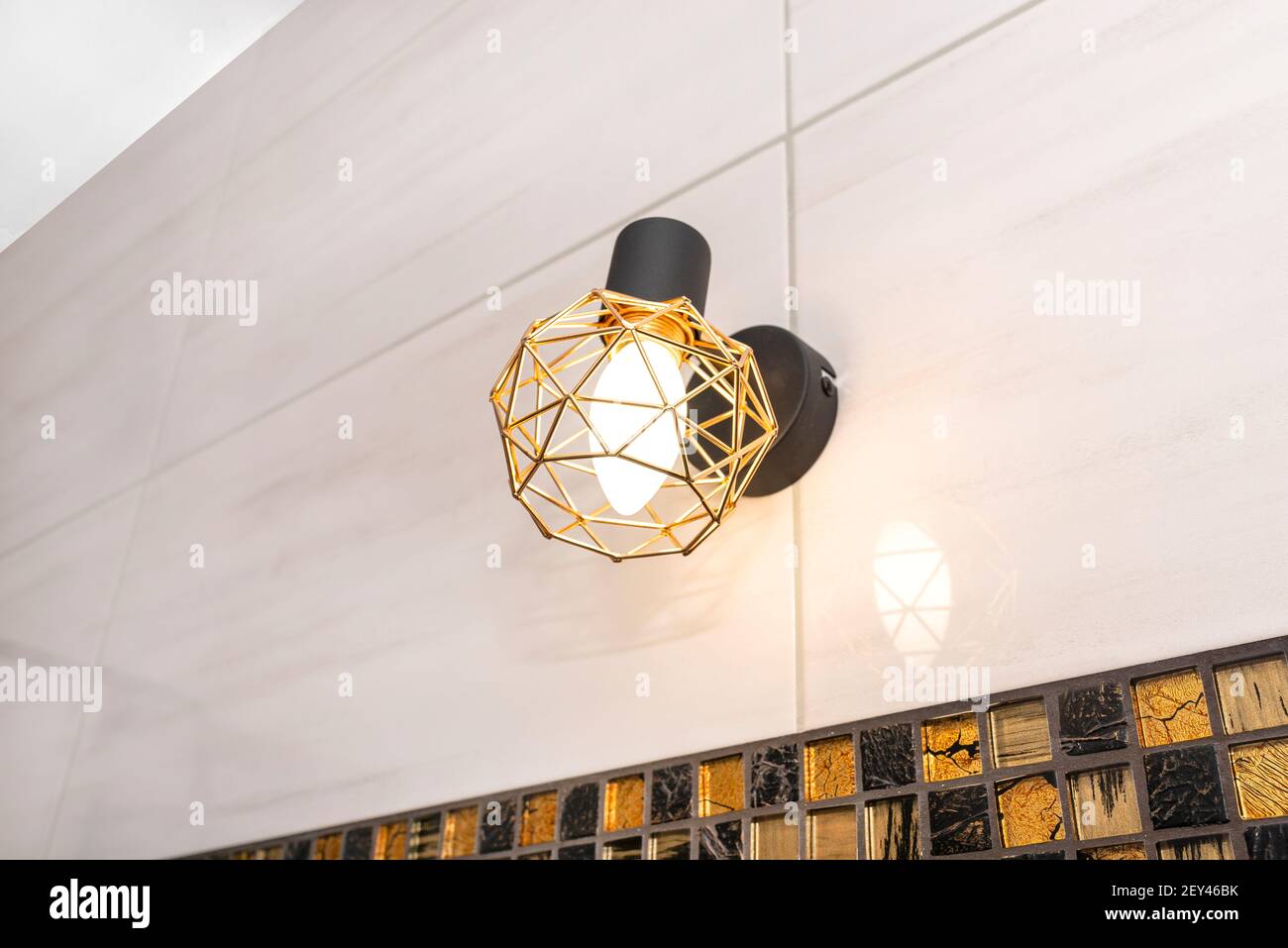 Classic yellow light bulb attached to the wall with ceramic tiles in