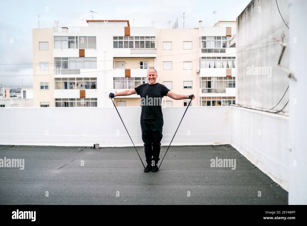 A man exercising with gum on the rooftop during self-confinement caused by pandemic Stock Photo