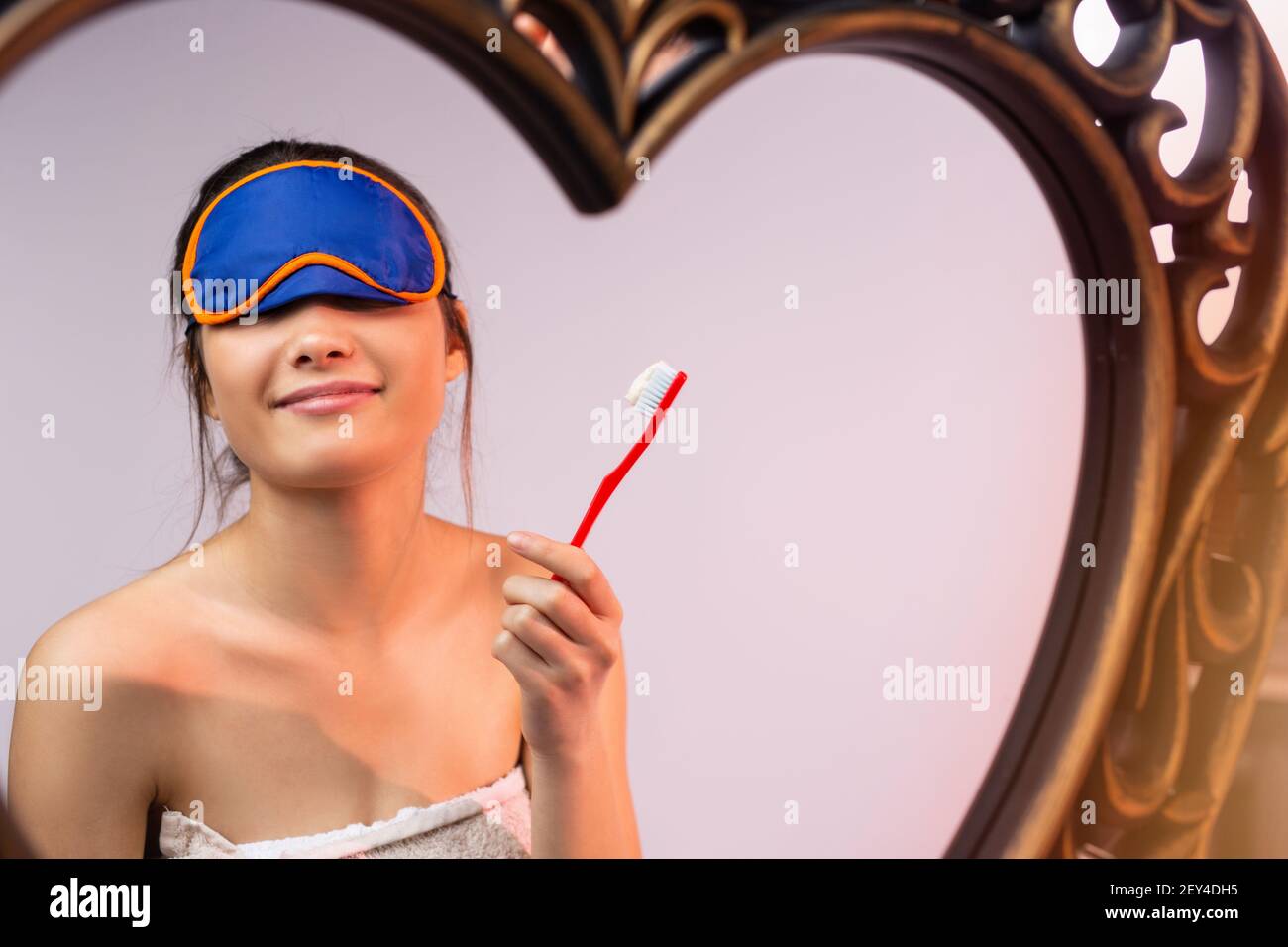 A with a blindfold is brushing her teeth in front of a mirror. Evening procedures. Home
