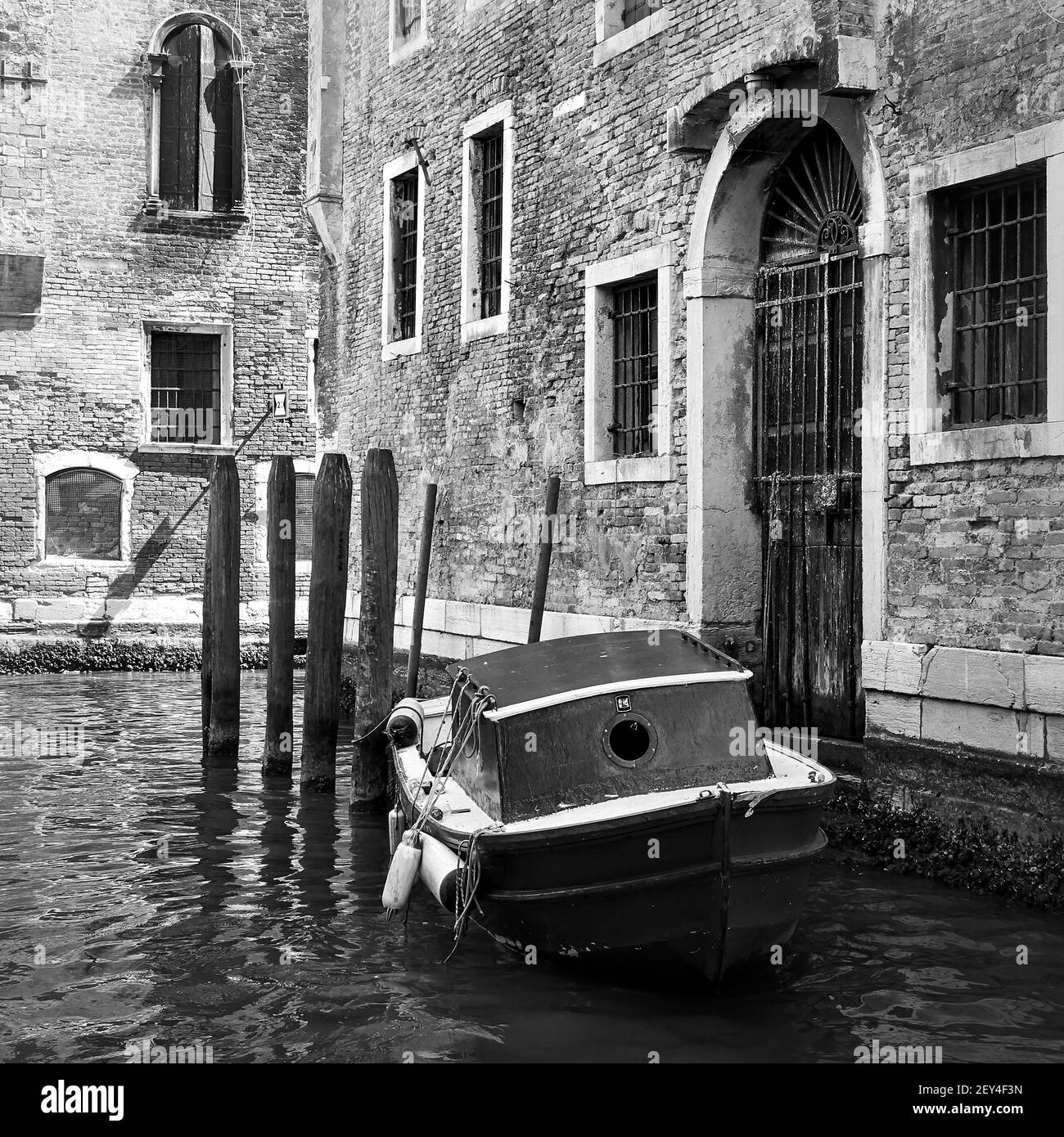 Venetian side canal with old boat, Venice, Italy. Black and white photography, cityscape Stock Photo