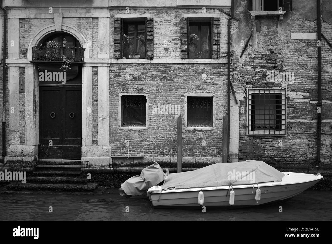Venetian canal with old house and moored boat, Venice, Italy. Black and white photography, cityscape Stock Photo