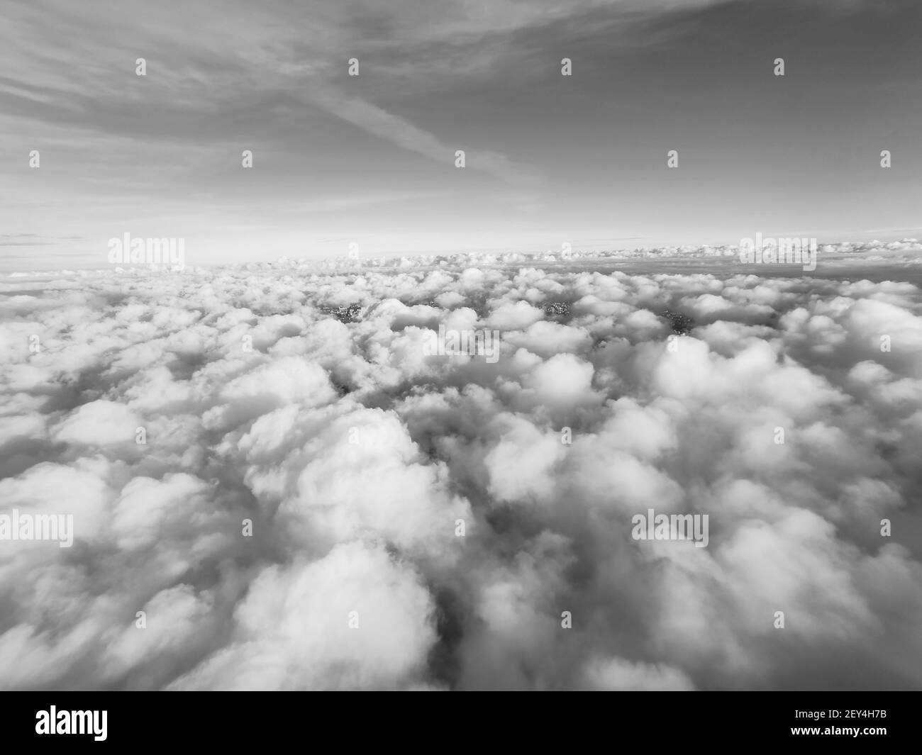 View from the plane to white volumetric thunderclouds and the space of the stratosphere, black and white, top view. Beautiful natural sky background. Stock Photo