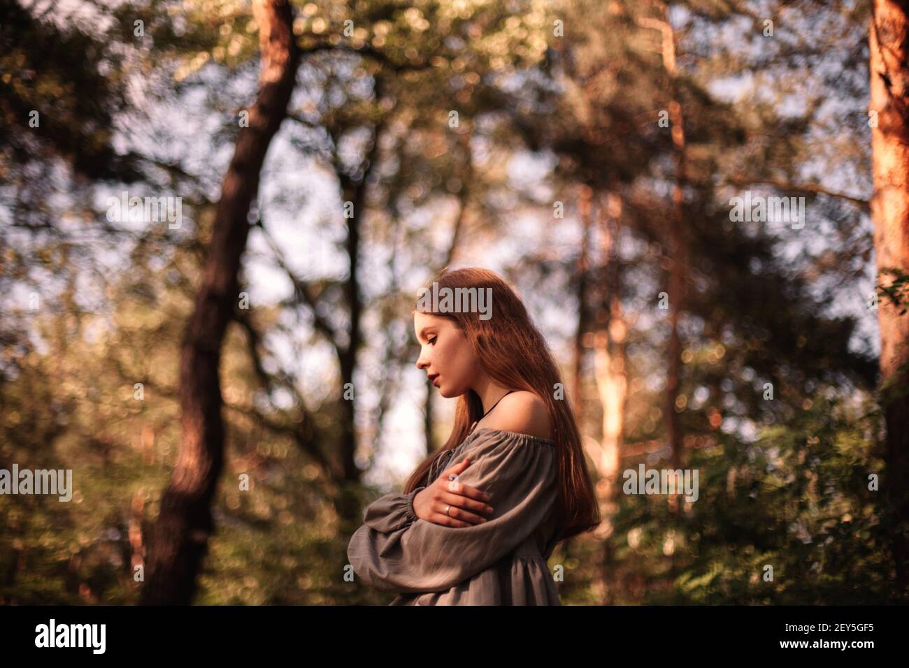 Side view of thoughtful teenage girl standing in forest during summer Stock Photo