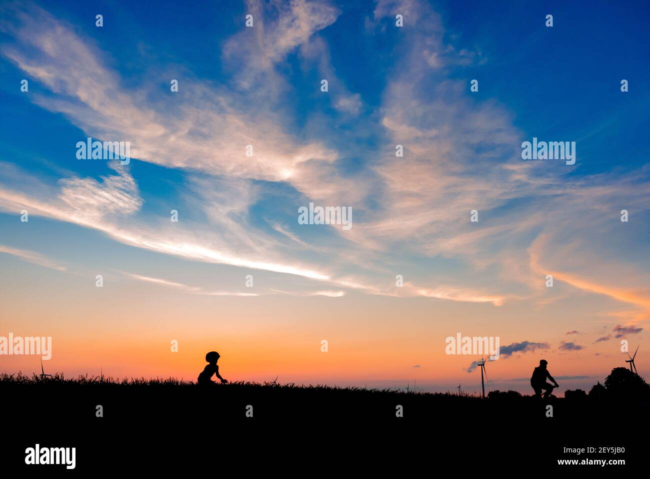 a father and son riding bicycles together in the sunset Stock Photo