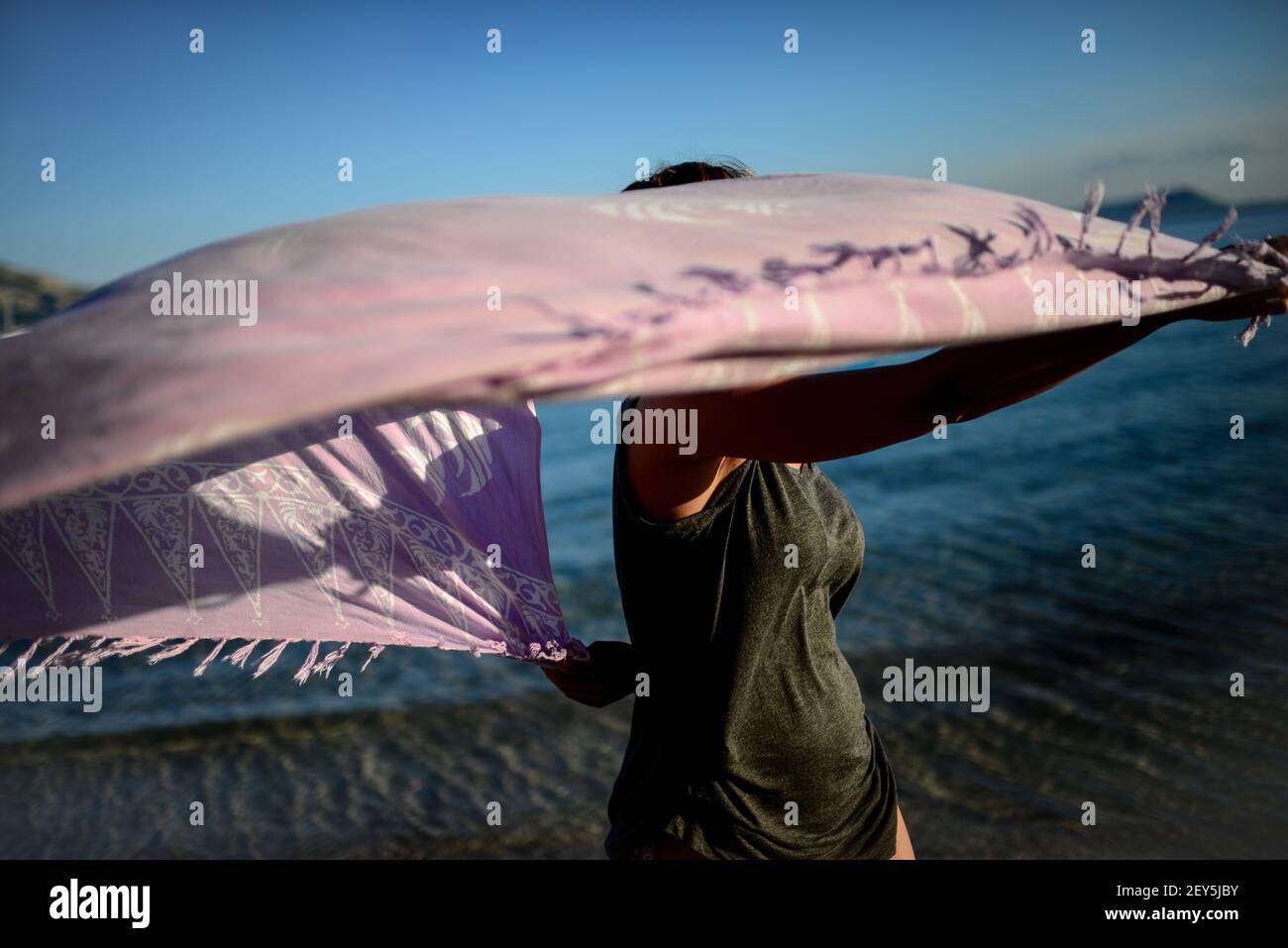 Young woman dances on the beach with sarong Stock Photo