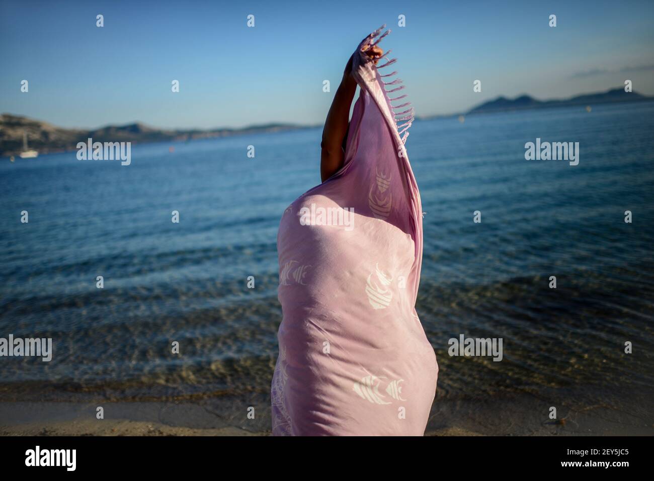 Young woman dances on the beach with sarong Stock Photo