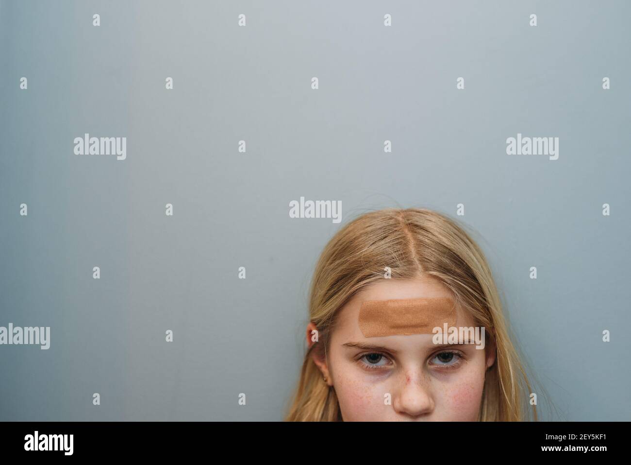 Young girl with bandaid on forehead cropped face with eyes and nose Stock Photo