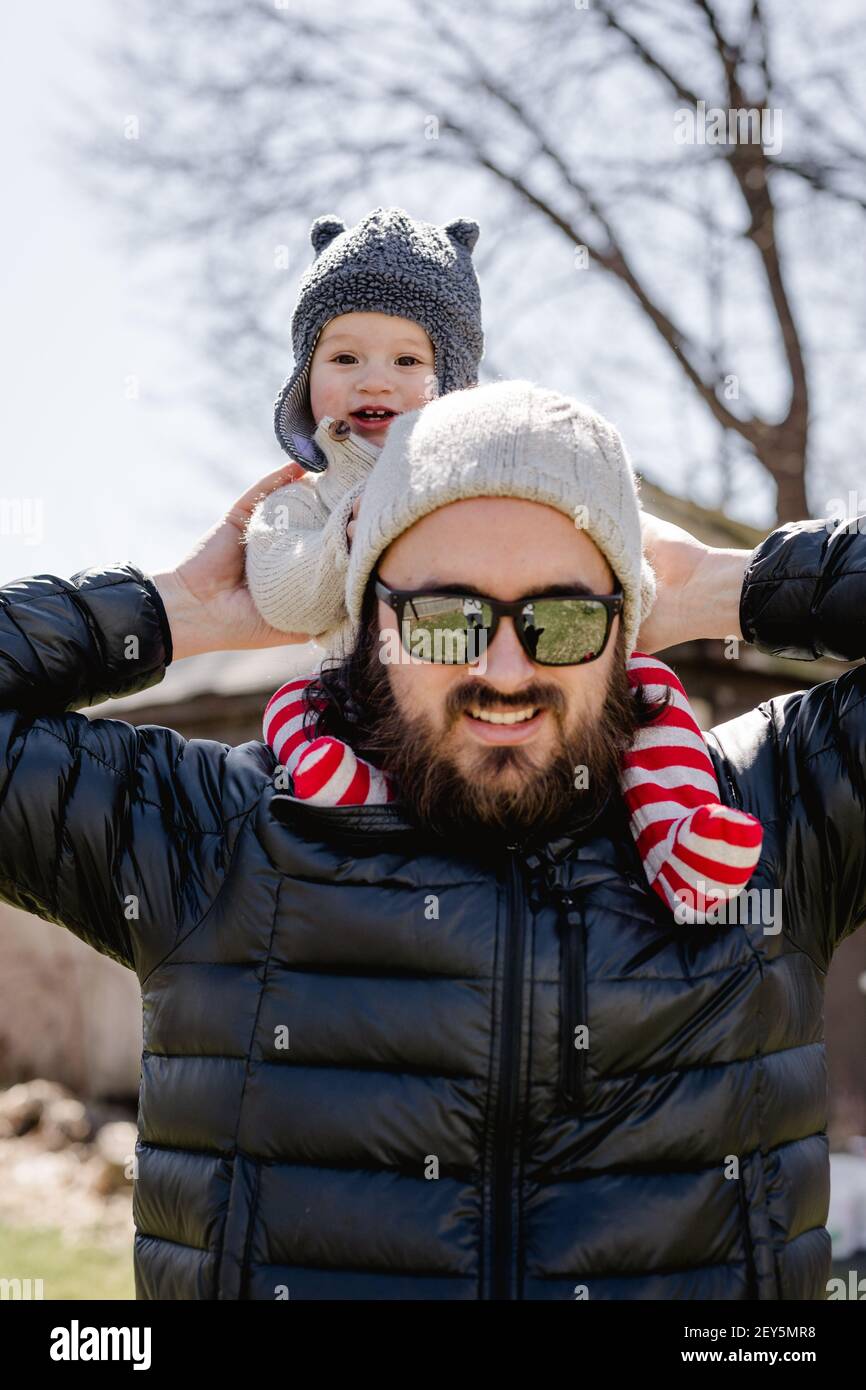 Happy baby on dad's shoulders in backyard on chilly afternoon Stock Photo