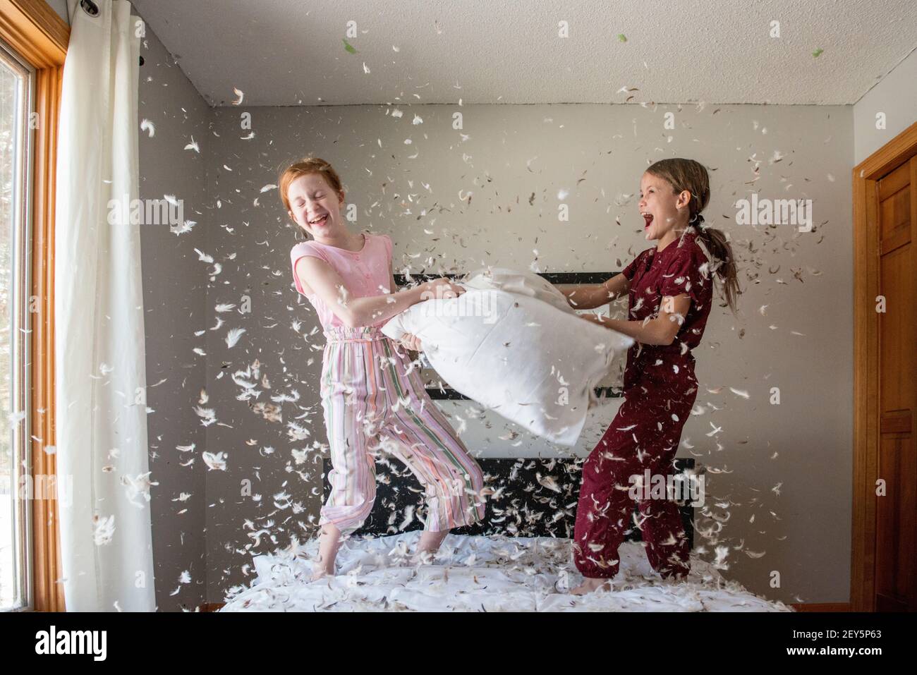 Two happy young girls having a feather pillow fight on the bed Stock Photo  - Alamy, image size:1300x957