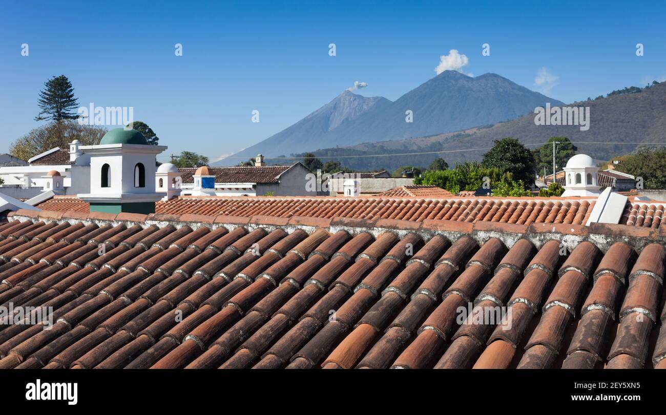 The Fuego (Fire) volcano emits a puff of ash alongside Acatenango volcano seen from a rooftop in Antigua, Guatemala Stock Photo