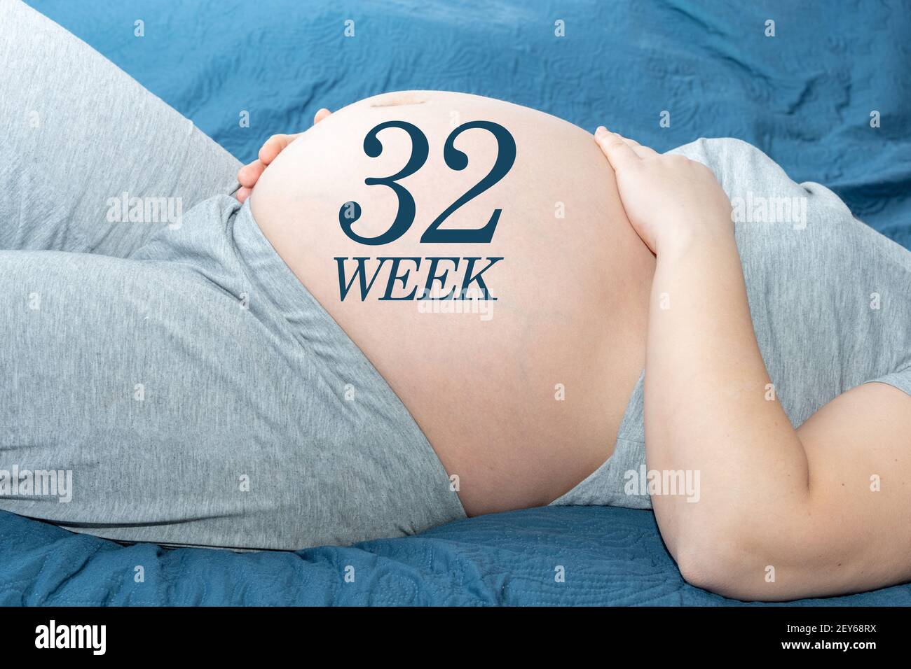 The concept of pregnancy. Beautiful belly of a pregnant woman with a 32 weeks calendar. A pregnant woman is expecting a baby. Time and waiting concept Stock Photo