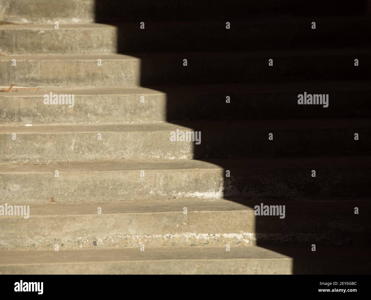 shadows cast on exterior cement stairs by afternoon sunlight in day time sun creating optical illusion of darkness emptiness angles or corrugation Stock Photo