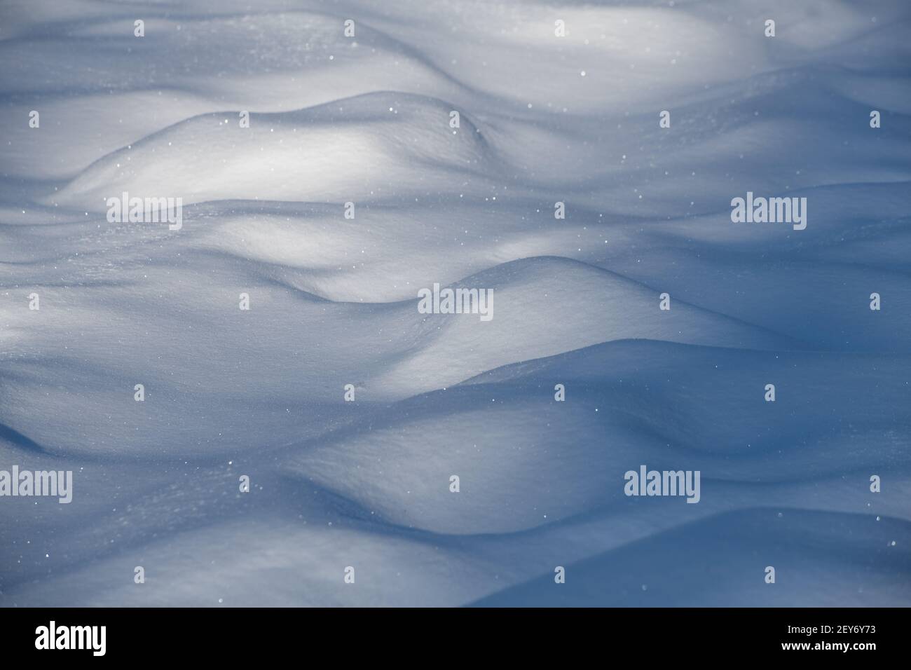 close up of mounds fo snow after fresh snow fall in winter cold temperatures sun shining on fresh snow crystals shadows behind bumps of snow in field Stock Photo