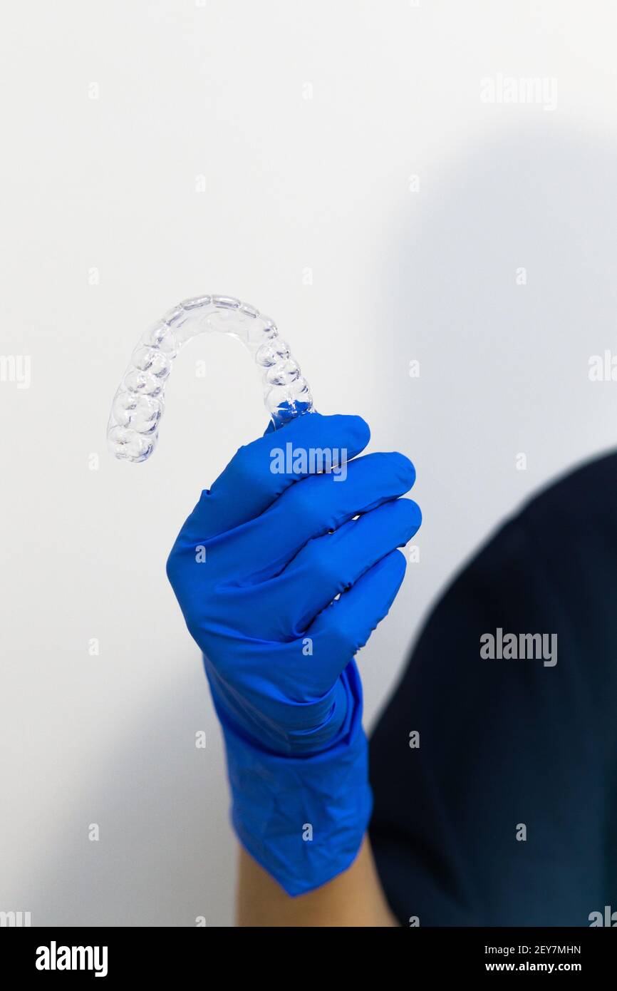 A vertical shot of a dentist with gloves holding a transparent dental ...