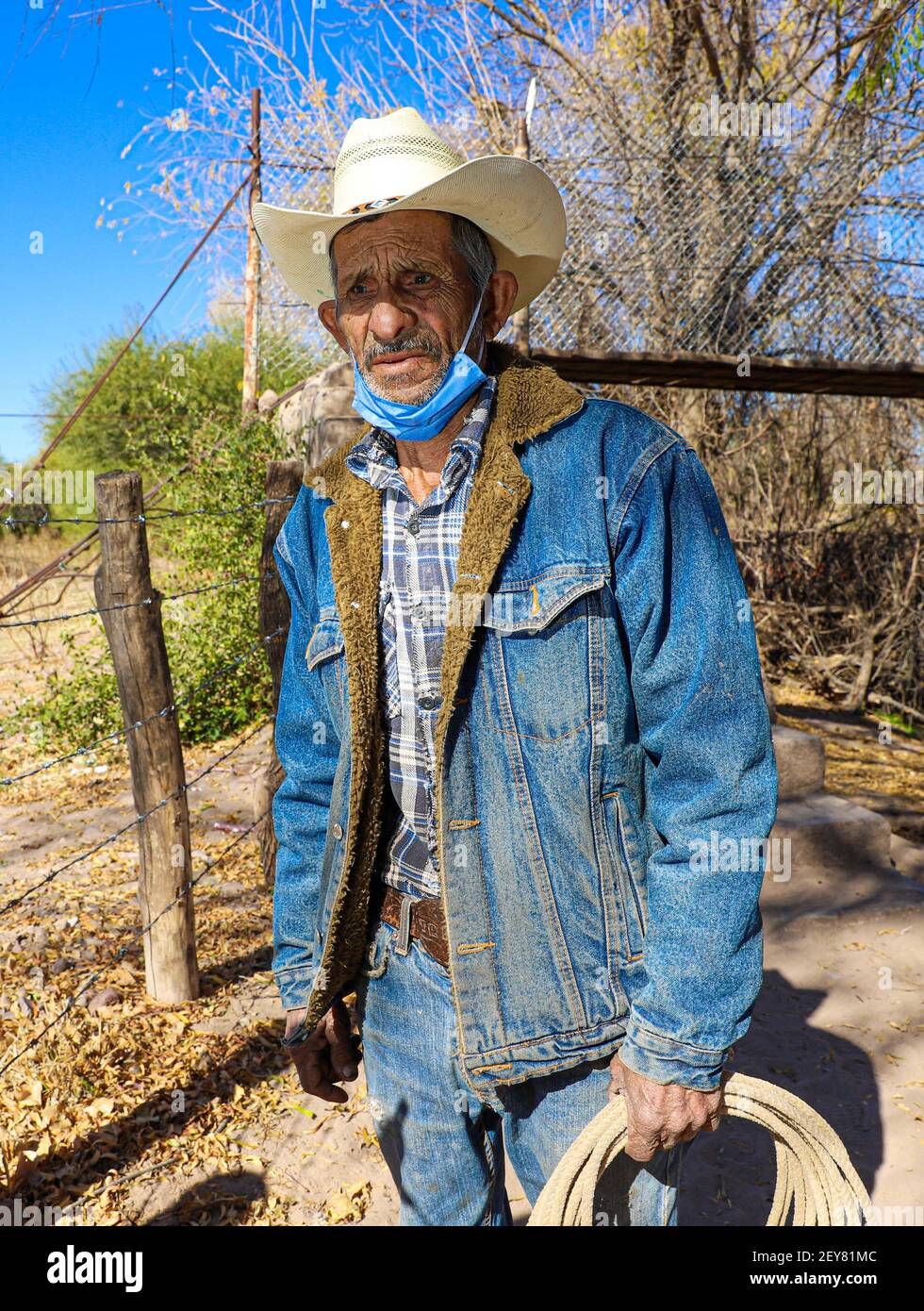 Portrait of a cowboy who wears a hat and a denim jacket in his hand a riata  or cattle rope in the town of Villa Hidalgo, Sonora, Mexico. Blue jeans,  Levi's, face
