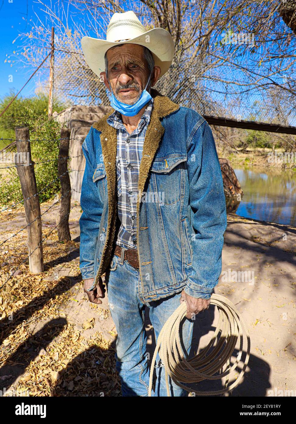 Portrait of a cowboy who wears a hat and a denim jacket in his hand a riata  or cattle rope in the town of Villa Hidalgo, Sonora, Mexico. Blue jeans,  Levi's, face