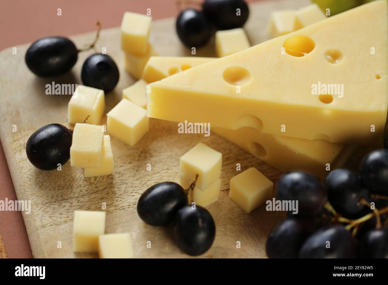 maasdamer cheese. Piece of cheese maasdam or maasdamer on wooden board on brown background.Hard cheeses. Dairy products.Healthy and tasty snack Stock Photo