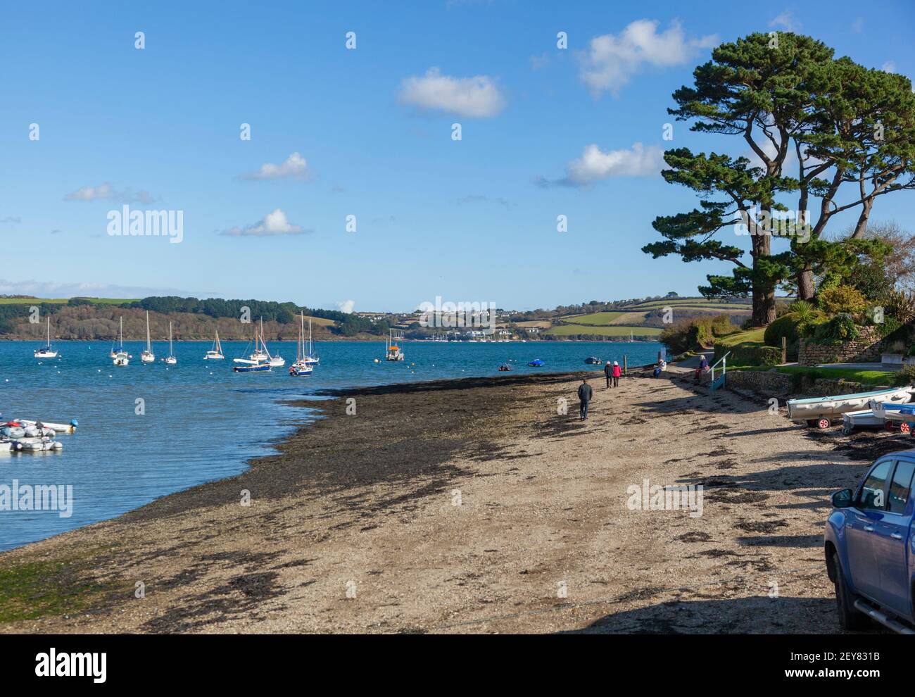 Coastal walkers stroll on the low tide shingle as they leave Mylor Yatch Harbour near Penryn and Falmouth, Cornwall ,UK Stock Photo