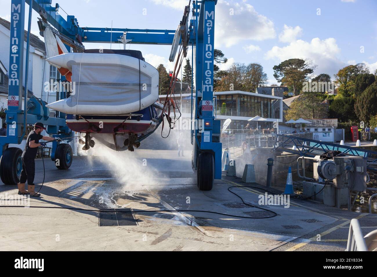 The hull of a boat is cleaned harbourside using a high pressure water jet spray at Mylor Yatch marina near Falmouth in Cornwall prior to storage. Stock Photo