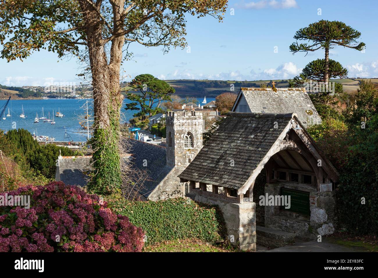 Views out to coastal waters across the roof and tower of  the Parish coastal Church of St Mylor in Cornwall Stock Photo