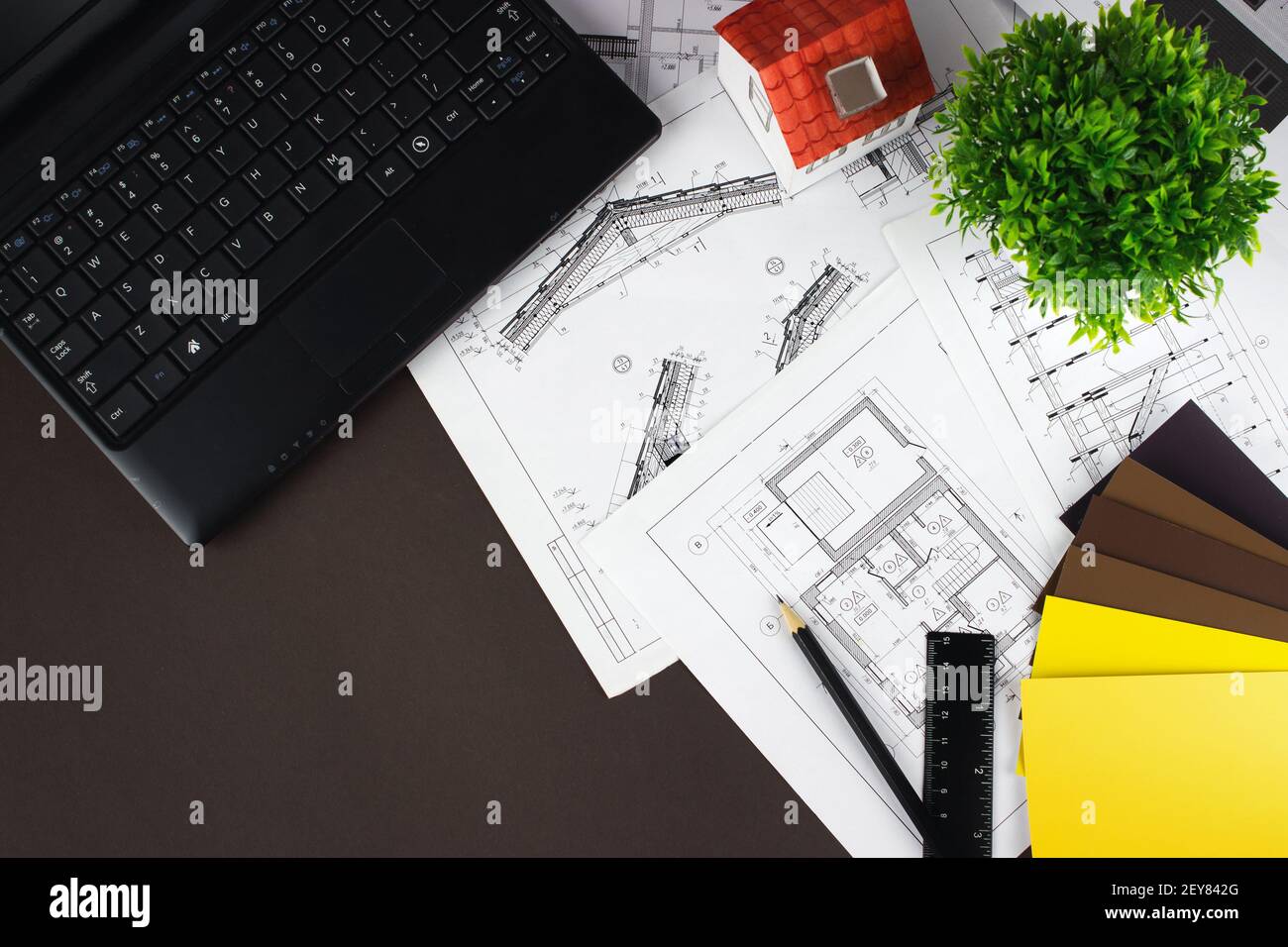 Architect workplace top view. White house on the construction drawings, laptop pen and color samples Stock Photo