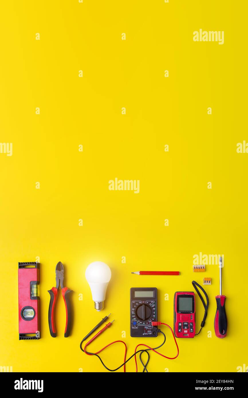 Different electrical tools on yellow background with shine. Components for use in electrical installations Stock Photo