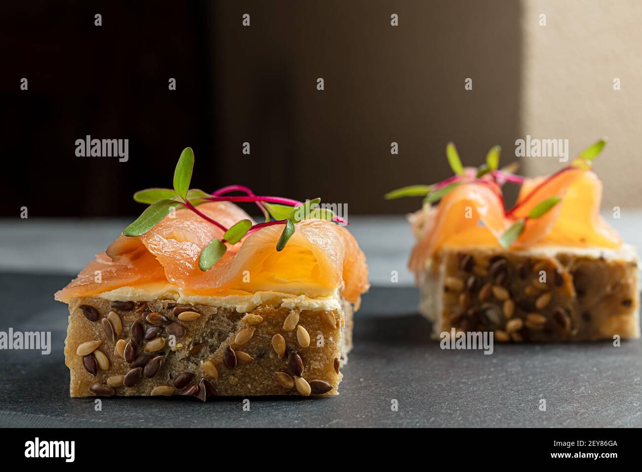 Cereal bread sandwiches with creamy cheese, smoked salmon and micro greens on a table Stock Photo
