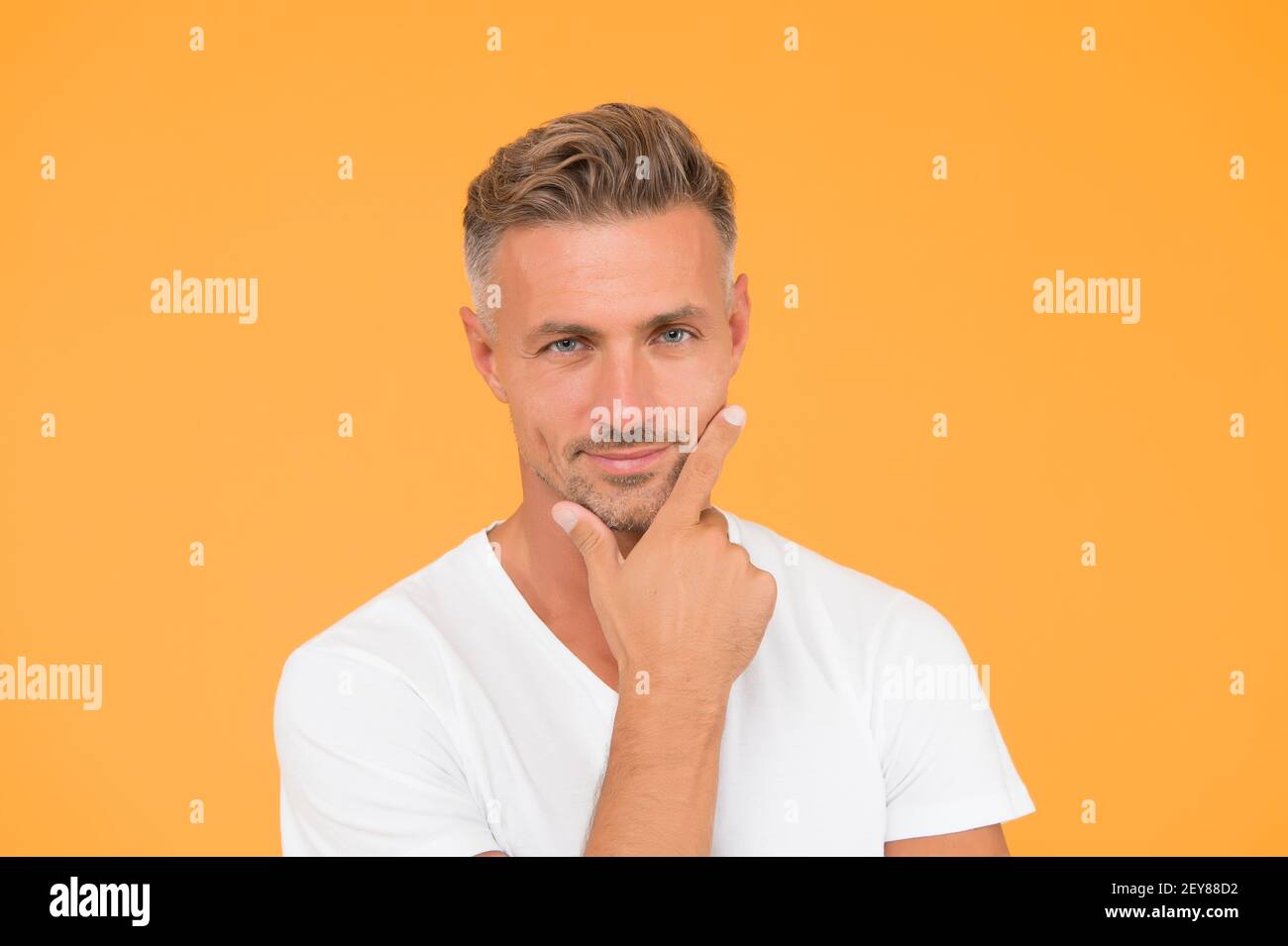 Ask barber to shave. Serious man touch beard hair yellow background