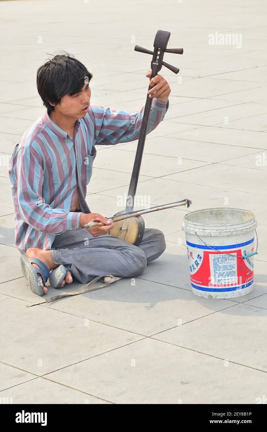 Beijing, China-May 26,2013: A beggar playing the erhu, Chinese traditional instrument, by the street. Selective focus points Stock Photo
