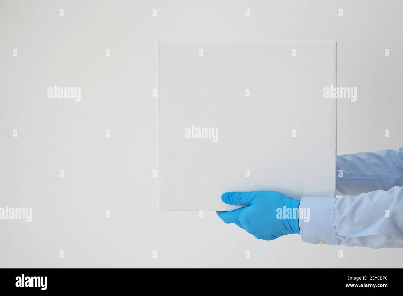 Delivery man holding cardboard boxes in medical gloves on white