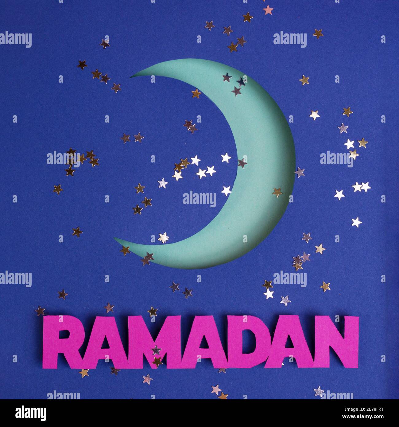 Crescent moon cut out of paper on a glitter background and paper word